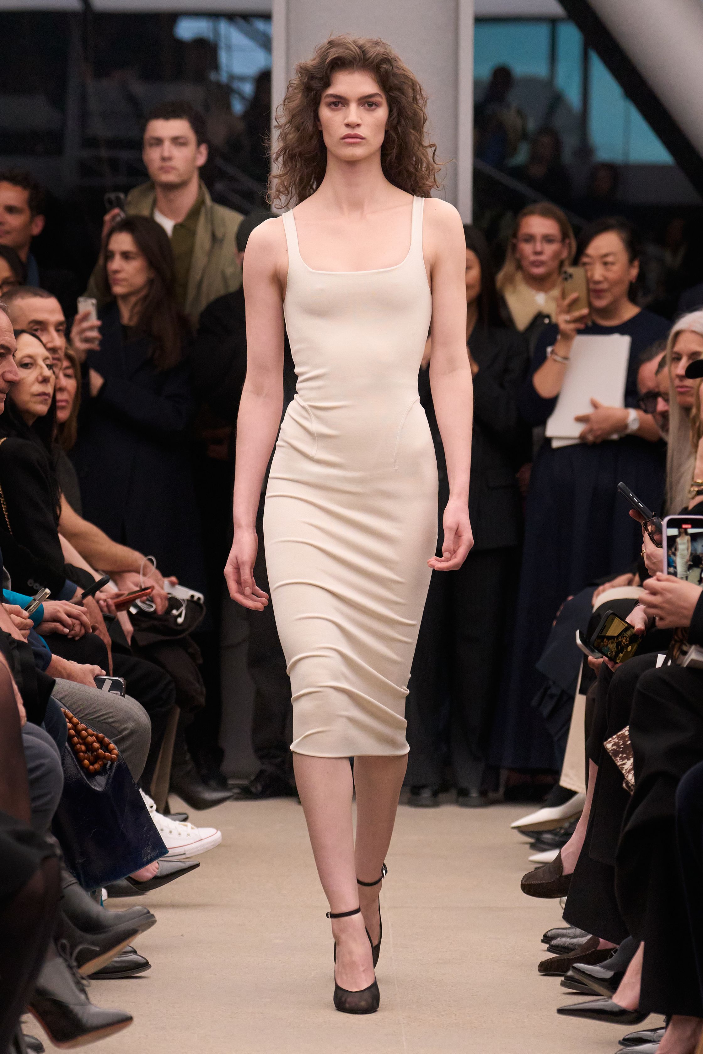 Alaïa继续以雕塑般的女性身体线条为核心，呈现极致精准的剪裁与材质张力。贴身针织长裙、立体外套与收腰大衣展现品牌标志性的曲线美学，整体色调以米色、酒红与深棕为主，营造出沉稳而性感的高级氛围。轮廓简洁却充满力量，既强调女性身体曲线，又通过结构性裁剪赋予服装雕塑般的建筑感，让极简主义与性感力量达到平衡-顽石频道趋势研究